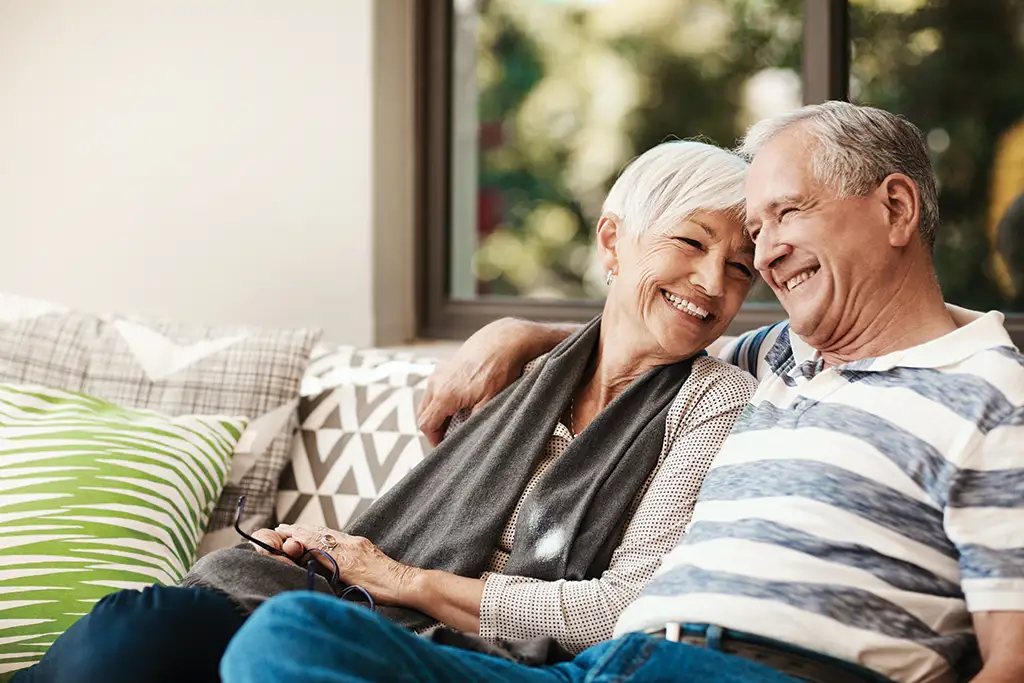 A happy elderly couple sitting together indoors