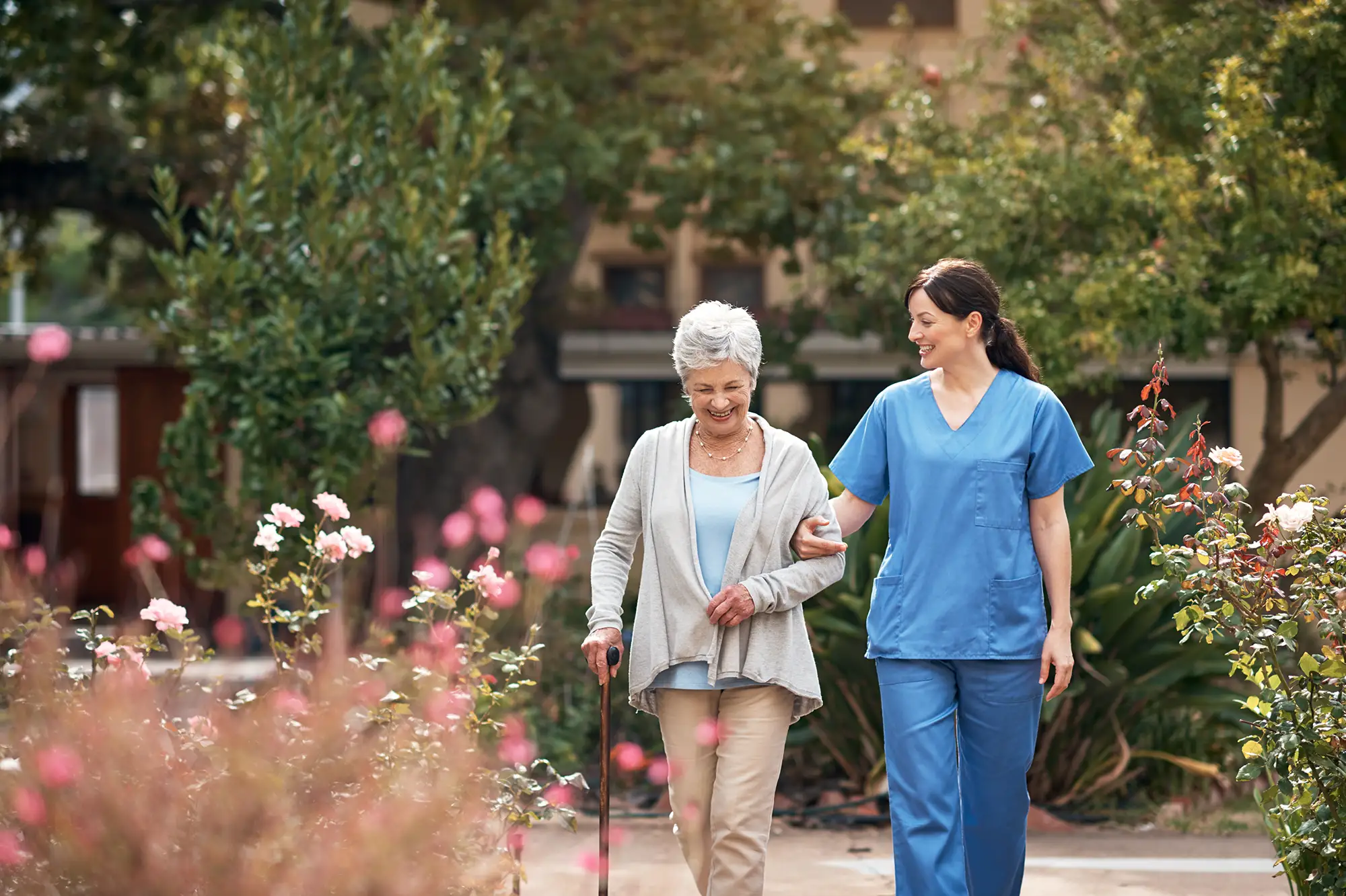 Staff assisting a resident in a landscaped garden