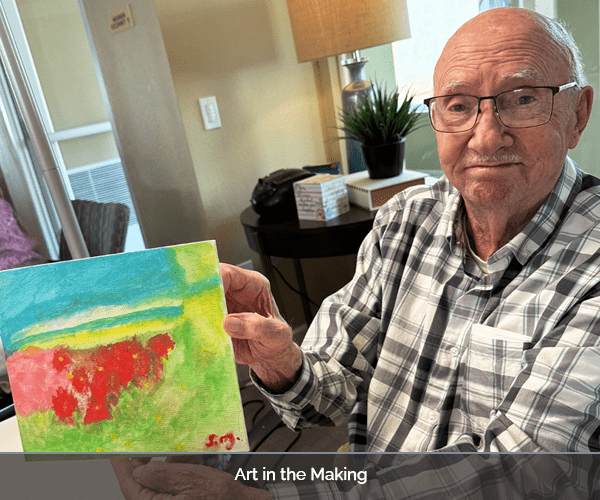 Resident showcasing their artwork in a bright room