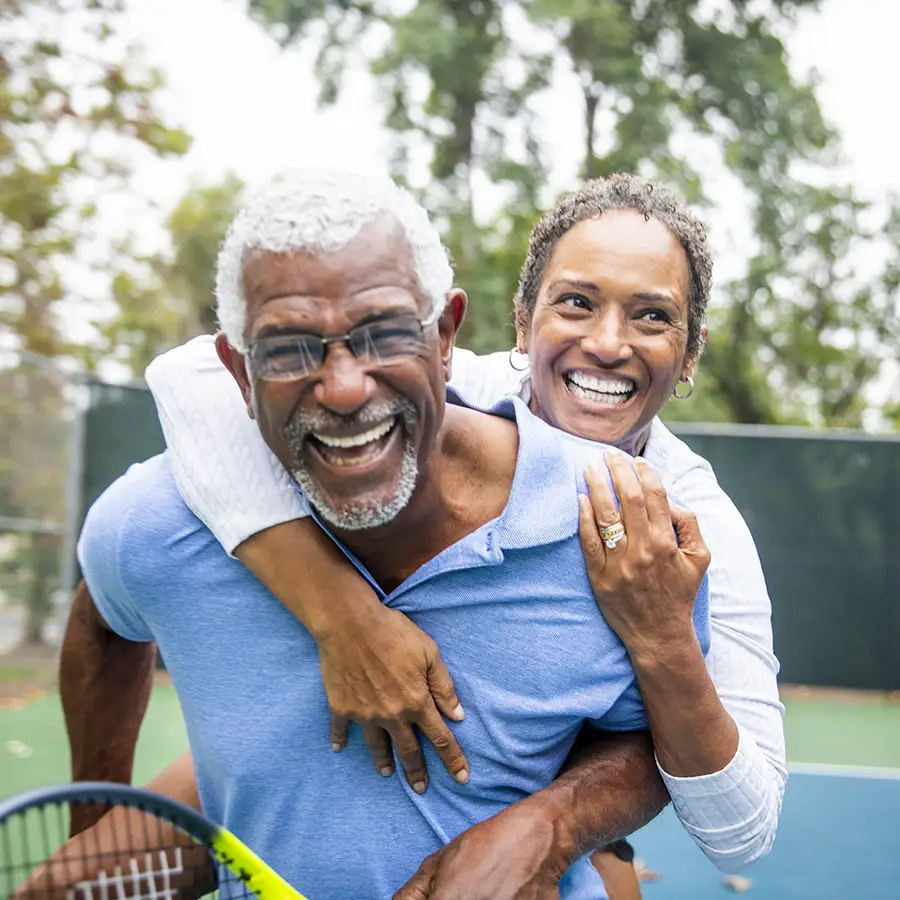 Two seniors enjoying tennis and smiling outdoors