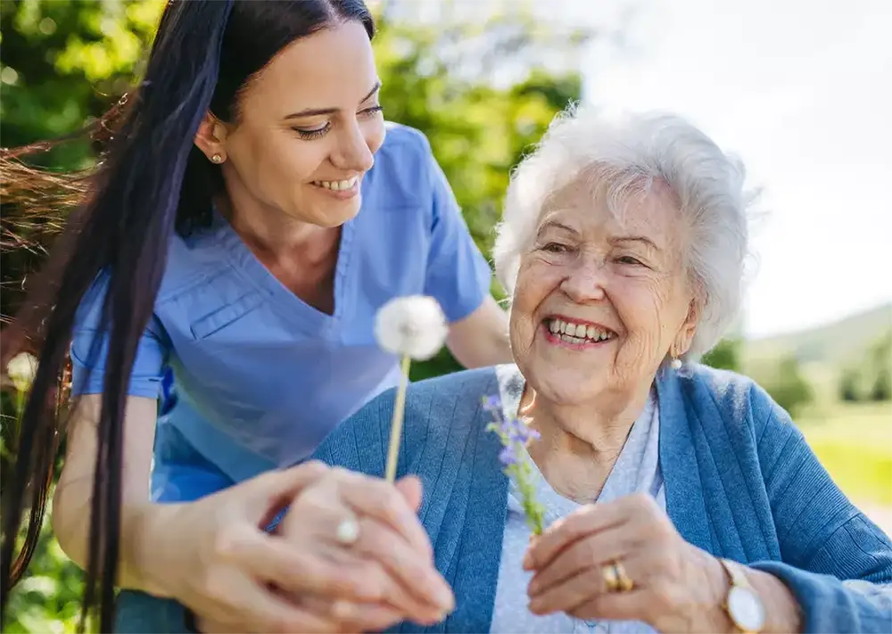 A caregiver and a senior enjoying time outdoors.