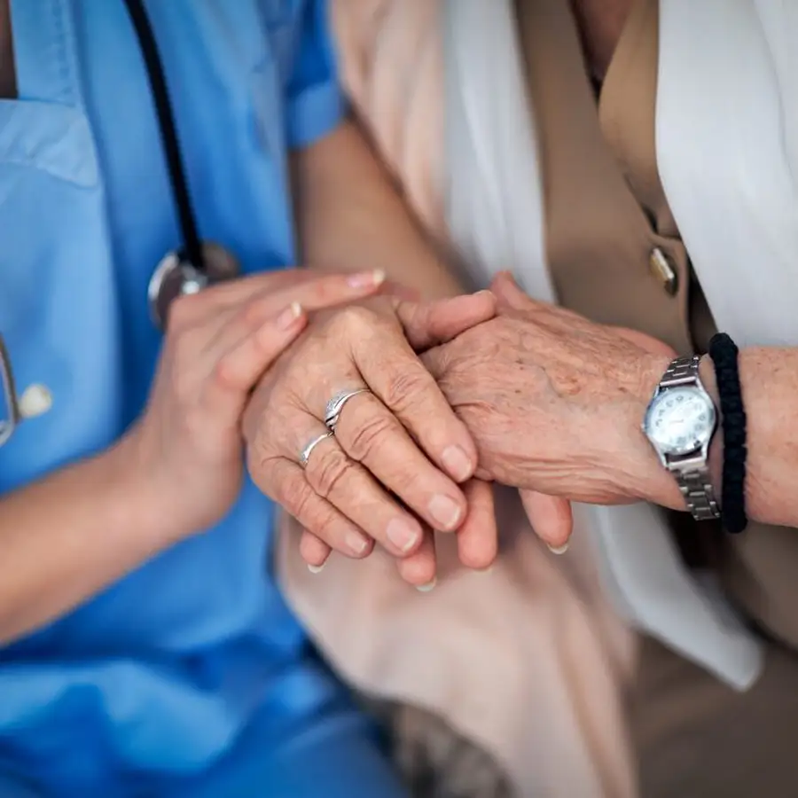 Close-up of a caregiver holding a resident's hand