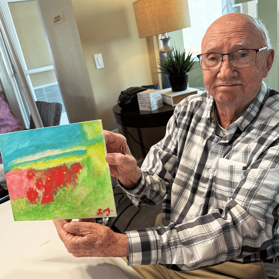 Senior resident showcasing their artwork in a common area