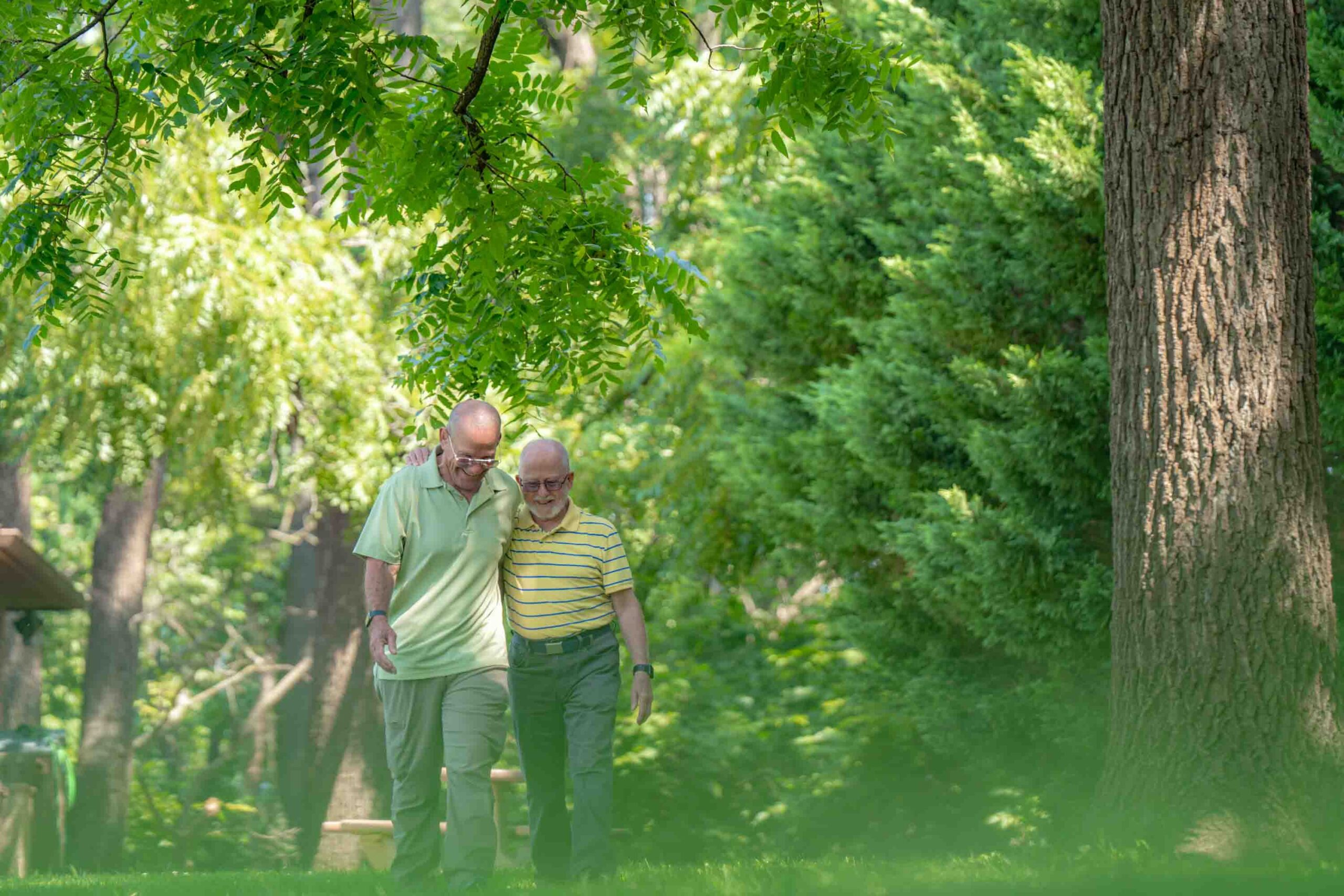 Two seniors walking together in a lush outdoor setting