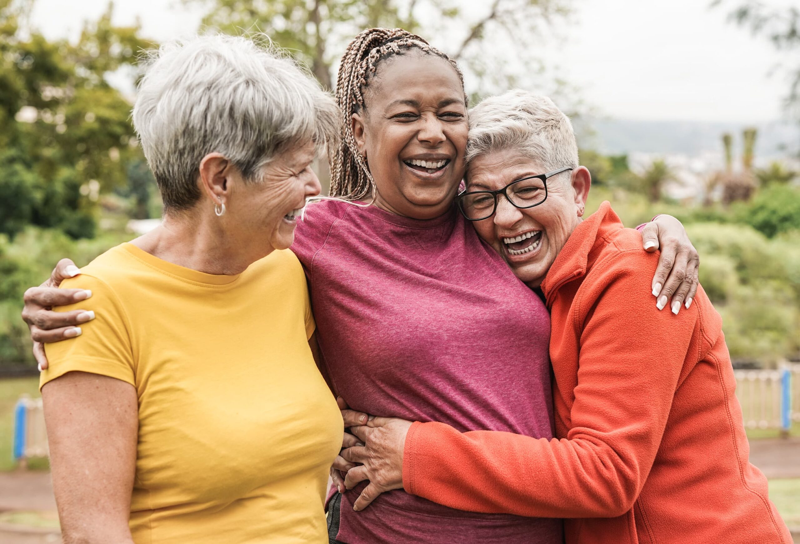 Three women laughing together in an outdoor setting