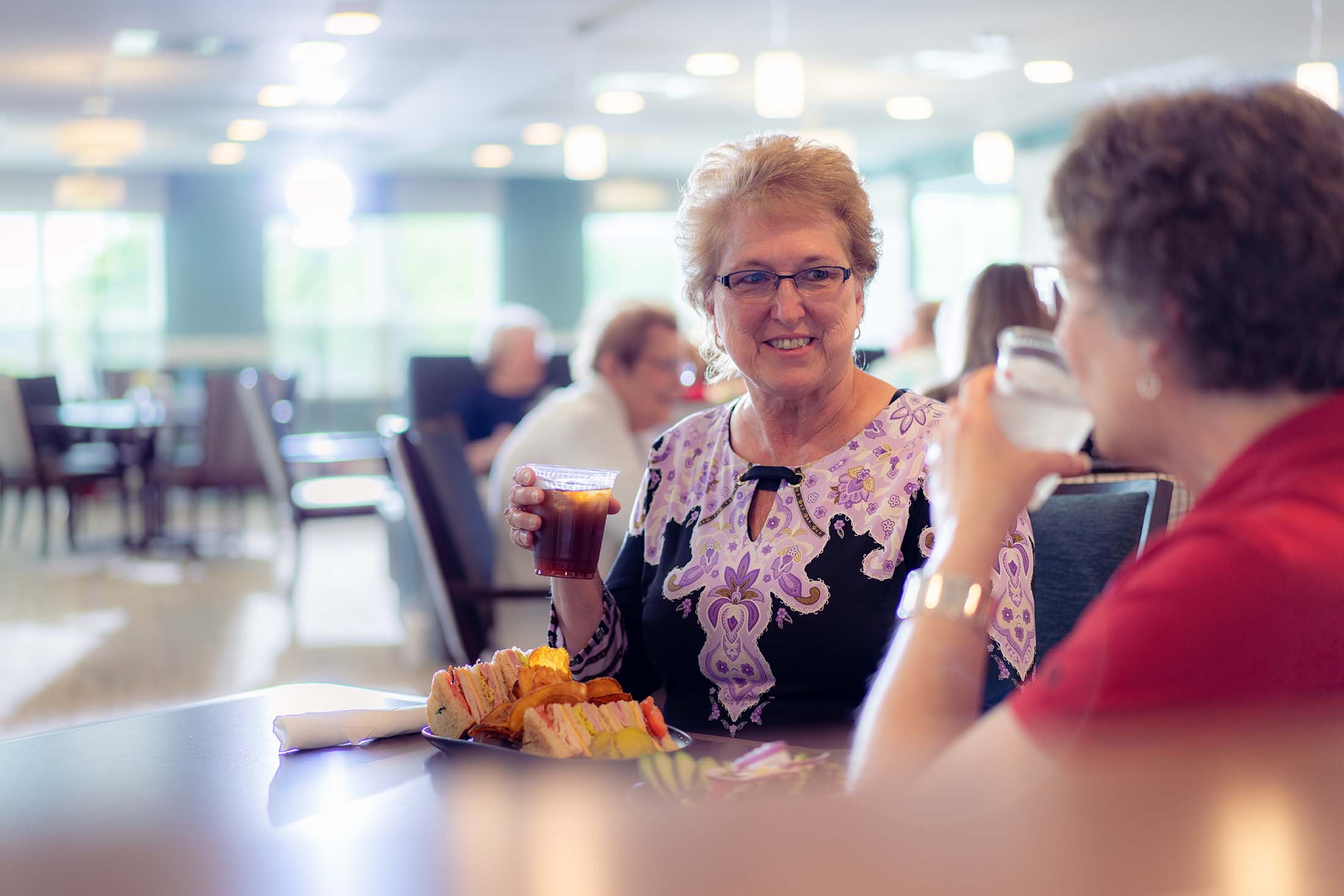 Residents enjoying sandwiches and drinks in the dining room