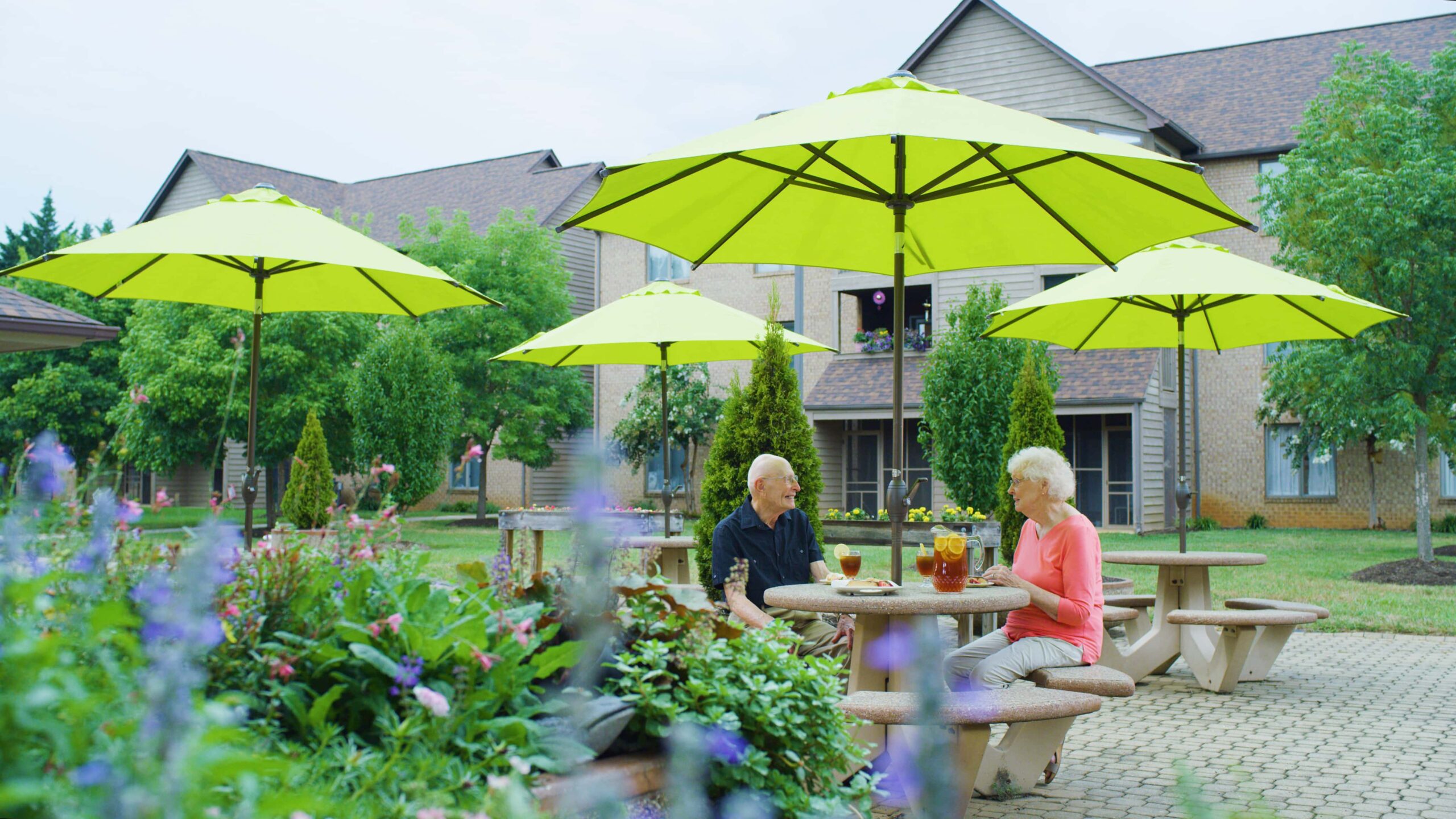 Residents enjoying drinks under bright umbrellas in the garden