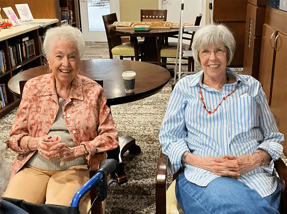 Two residents sitting in a common area, smiling