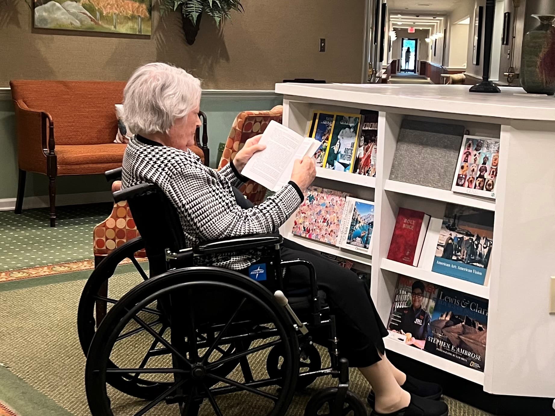 Resident reading in a common area with shelves