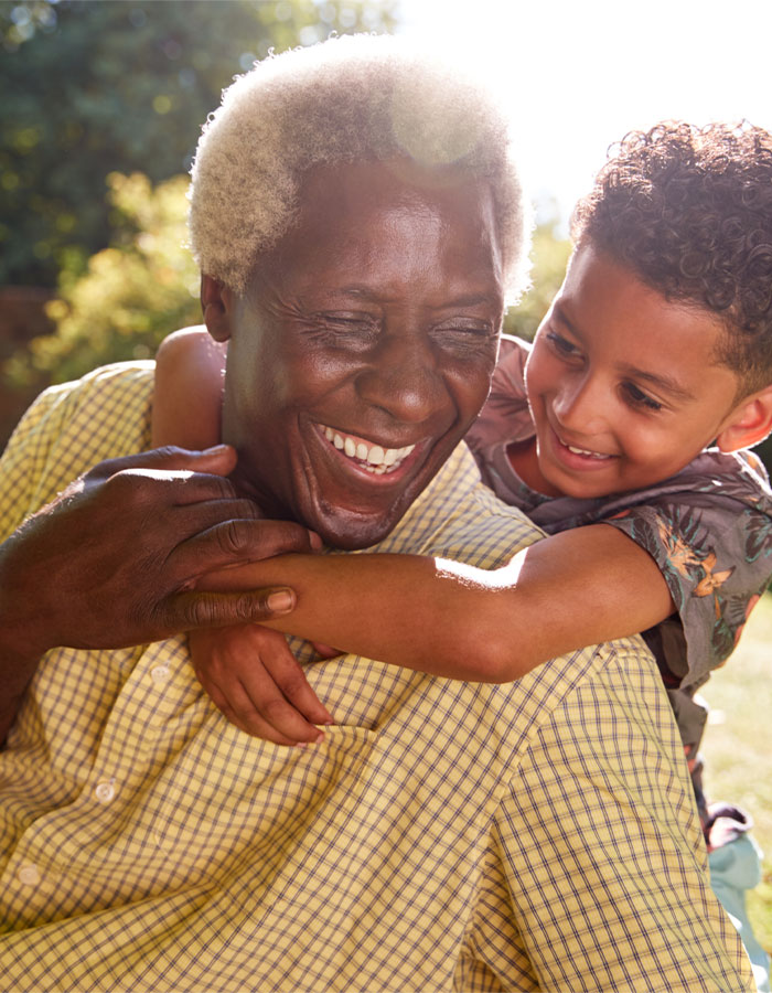 Elderly man sharing a joyful moment with a child outdoors