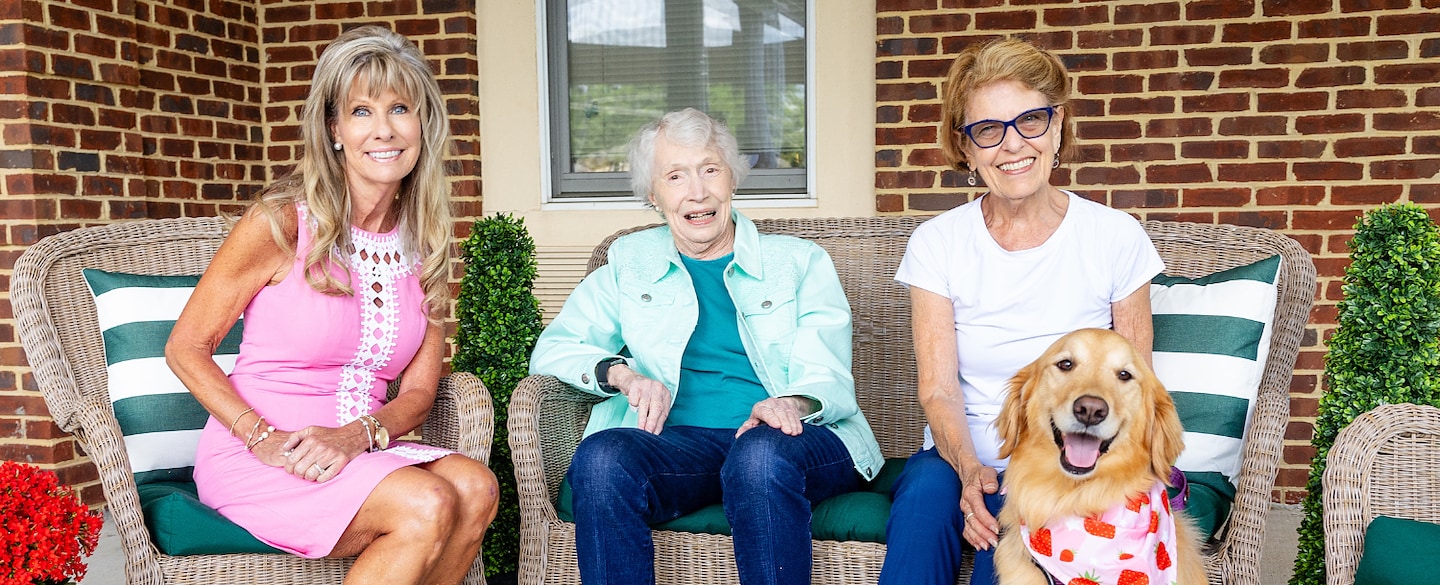 Residents enjoying time with staff and a dog outside