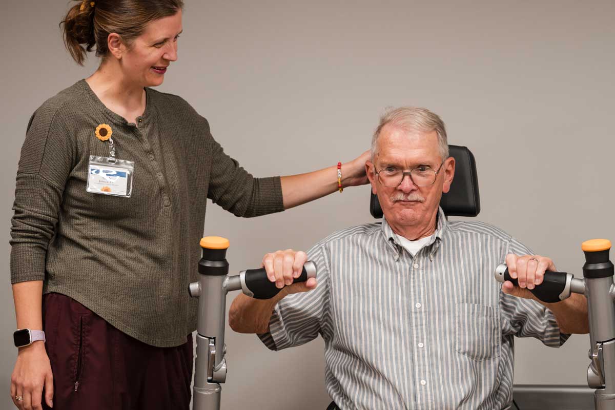 Senior resident engaged in physical therapy with staff support