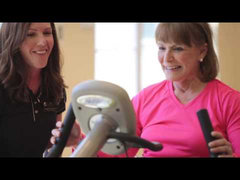 Resident exercising with trainer in fitness area