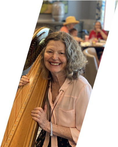 Resident smiling with a harp in a lively common area