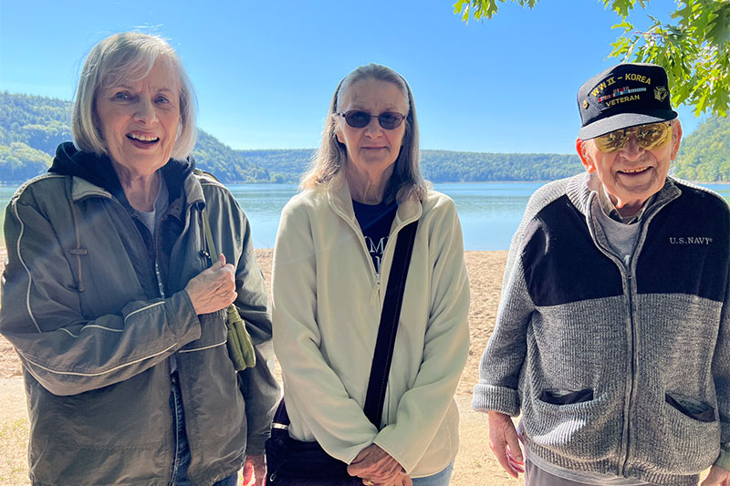 Three residents enjoying a sunny outdoor moment by the lake