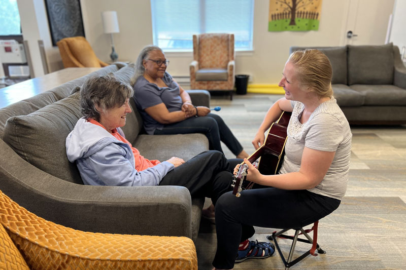 Resident enjoying music in a common area with staff member