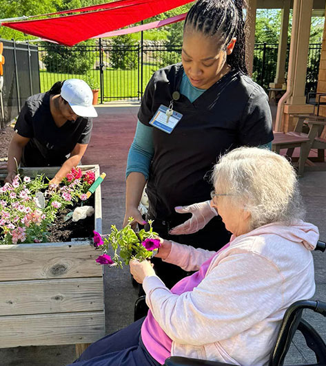 Staff assisting resident with gardening activities