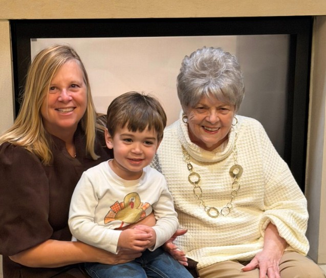 A woman seated with a child and an elderly woman in a cozy setting