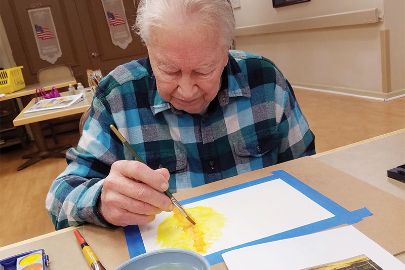 Resident painting in an activity room