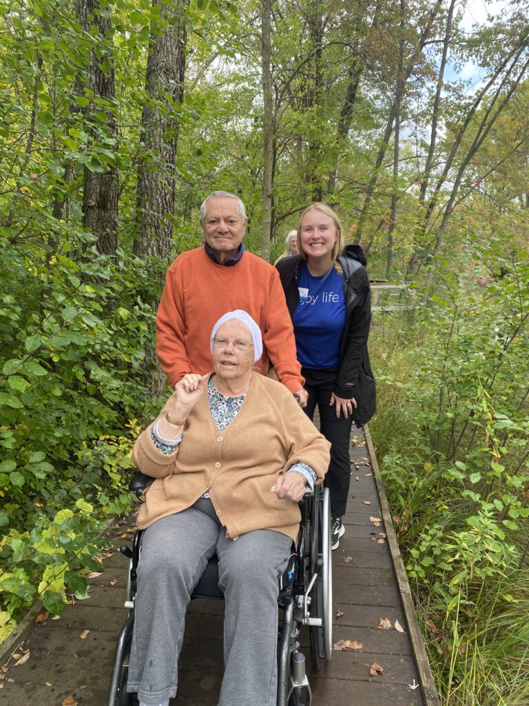A caregiver with two residents on a nature path