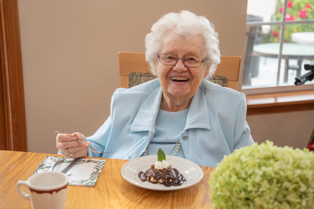 A smiling resident enjoying dessert in a dining room