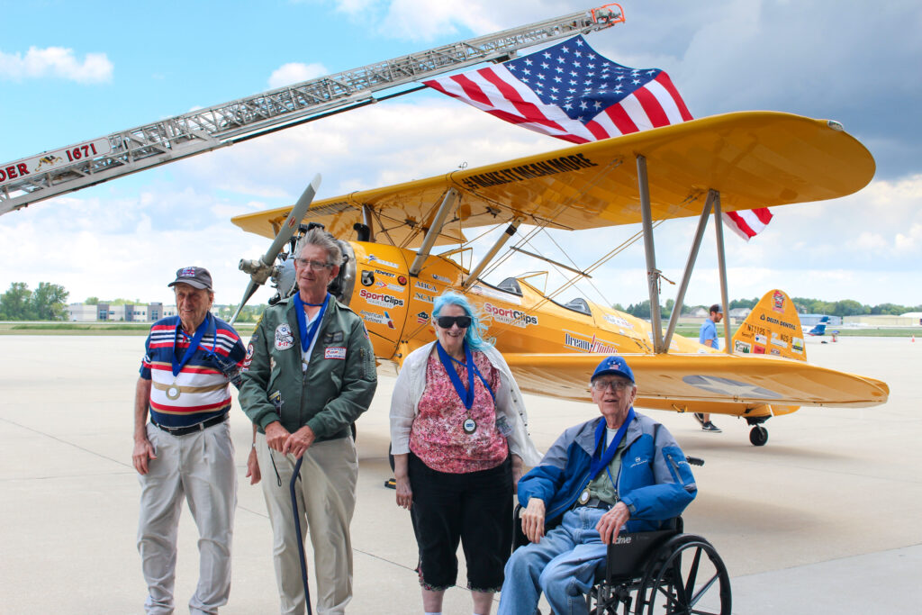 Veterans posing with a biplane at an airshow