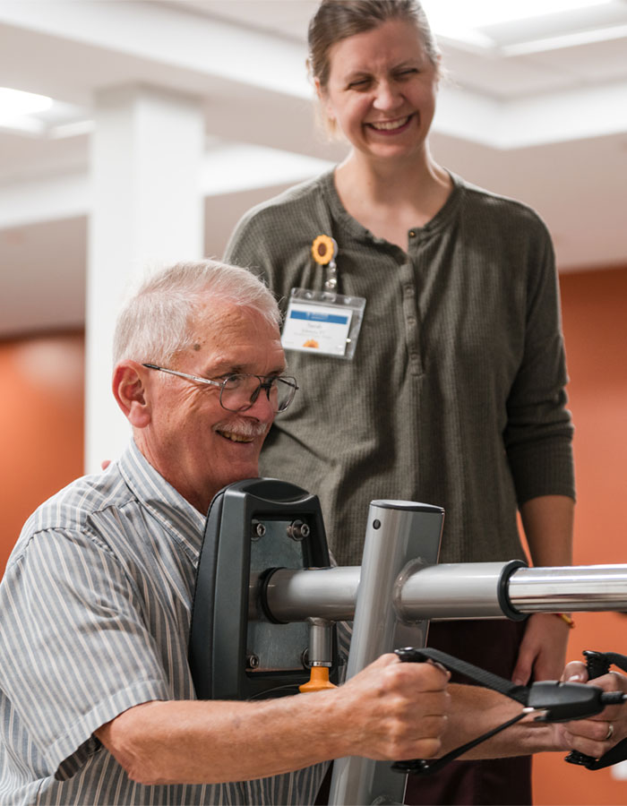Resident exercising with staff assistance in an activity room