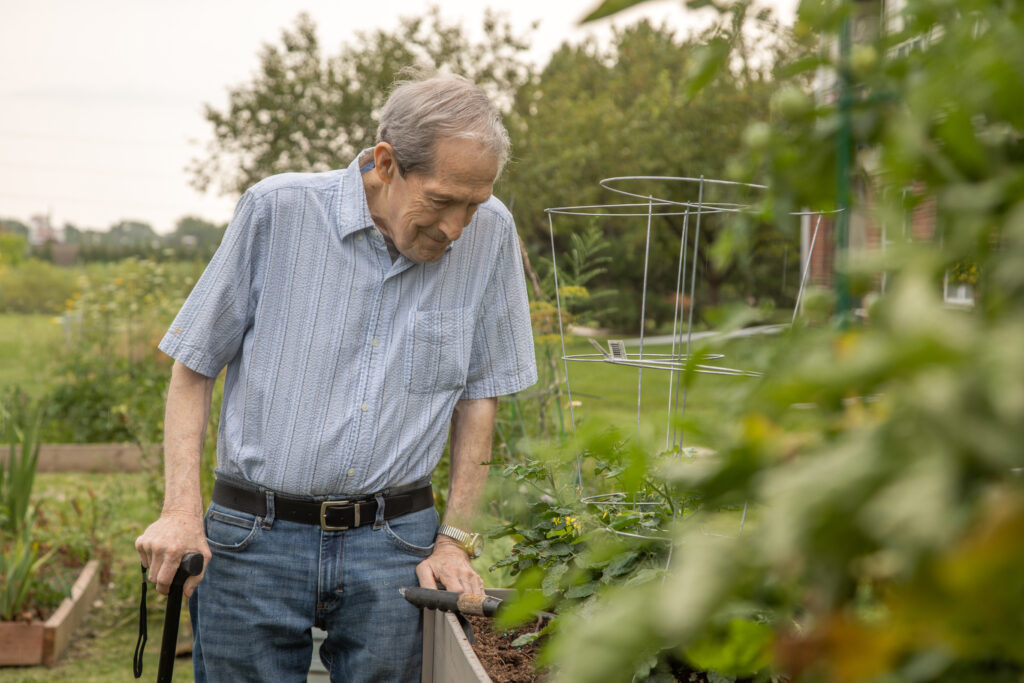 Resident enjoying gardening in a lush outdoor space