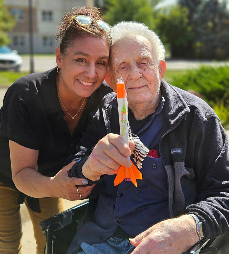 Resident with staff member outdoors holding a rocket toy