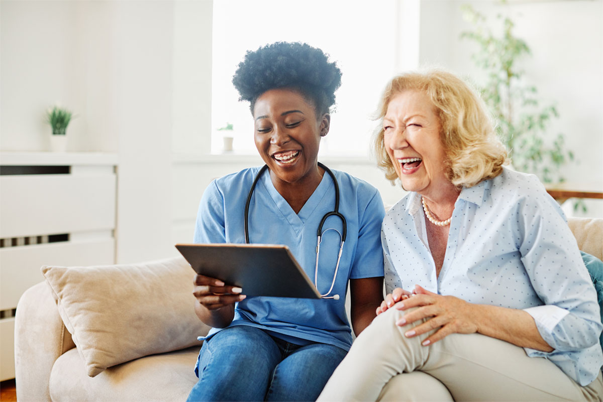 A caregiver and resident joyfully engaging with a tablet