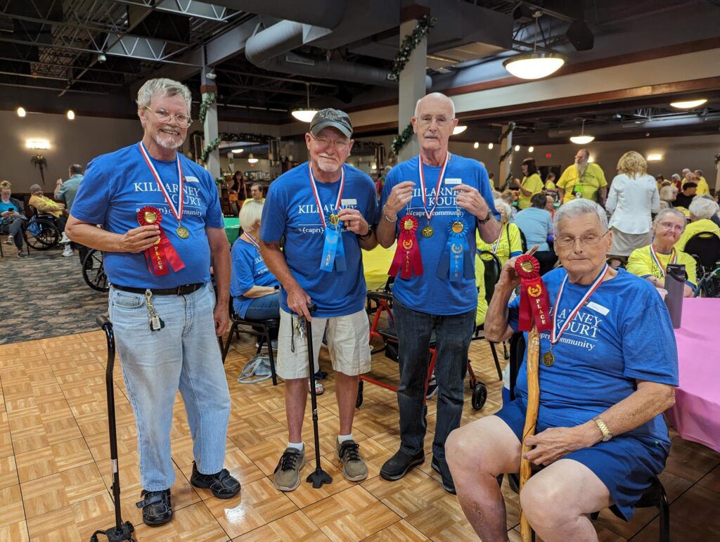 Residents holding ribbons and medals in a community room