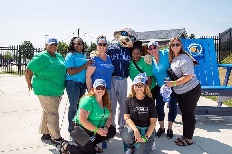 Staff members posing with a mascot in an outdoor area