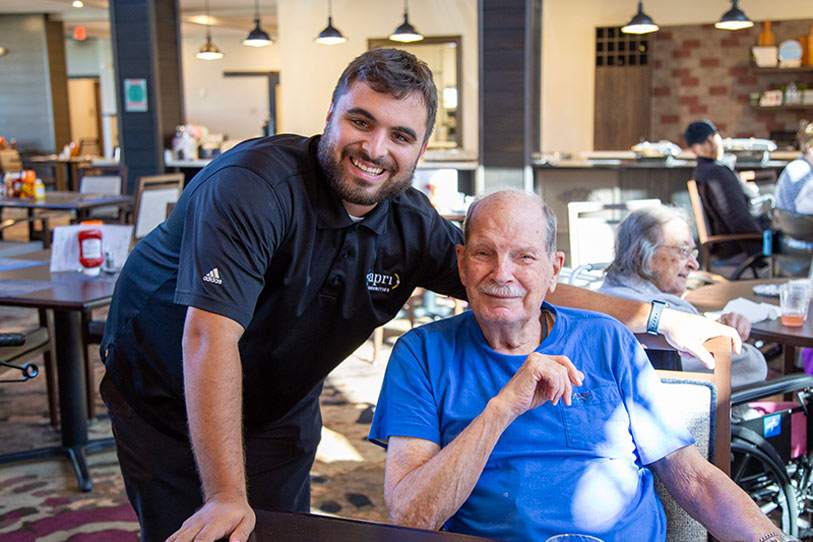 Staff member posing with a resident in the dining area