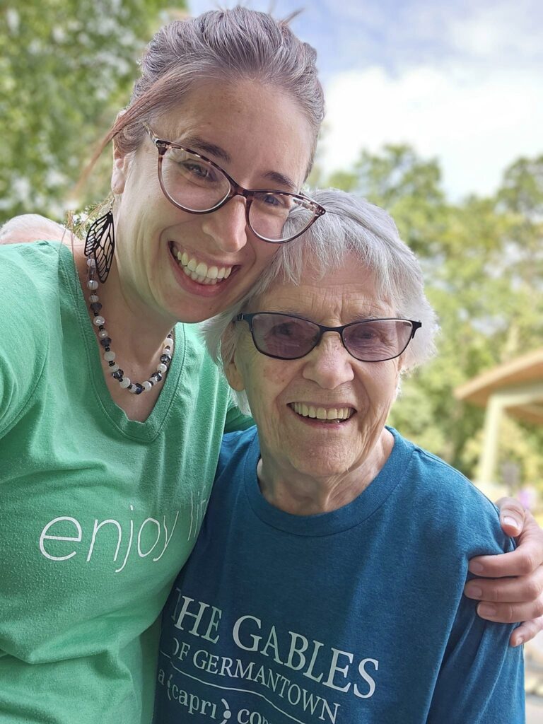 Caregiver and resident posing outdoors, smiling together