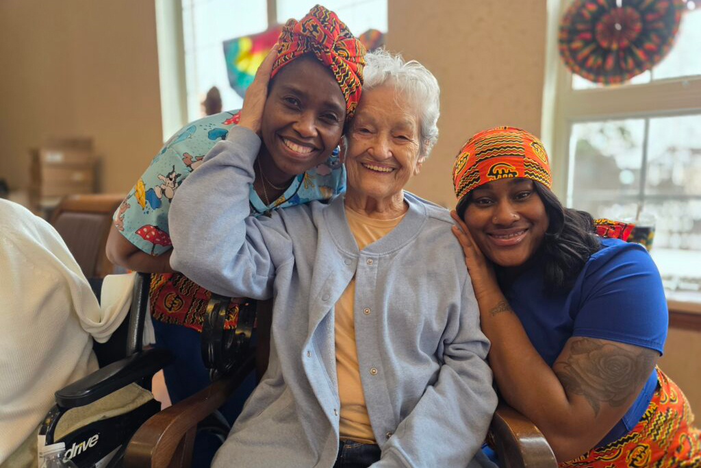 Three residents and staff sharing a joyful moment together