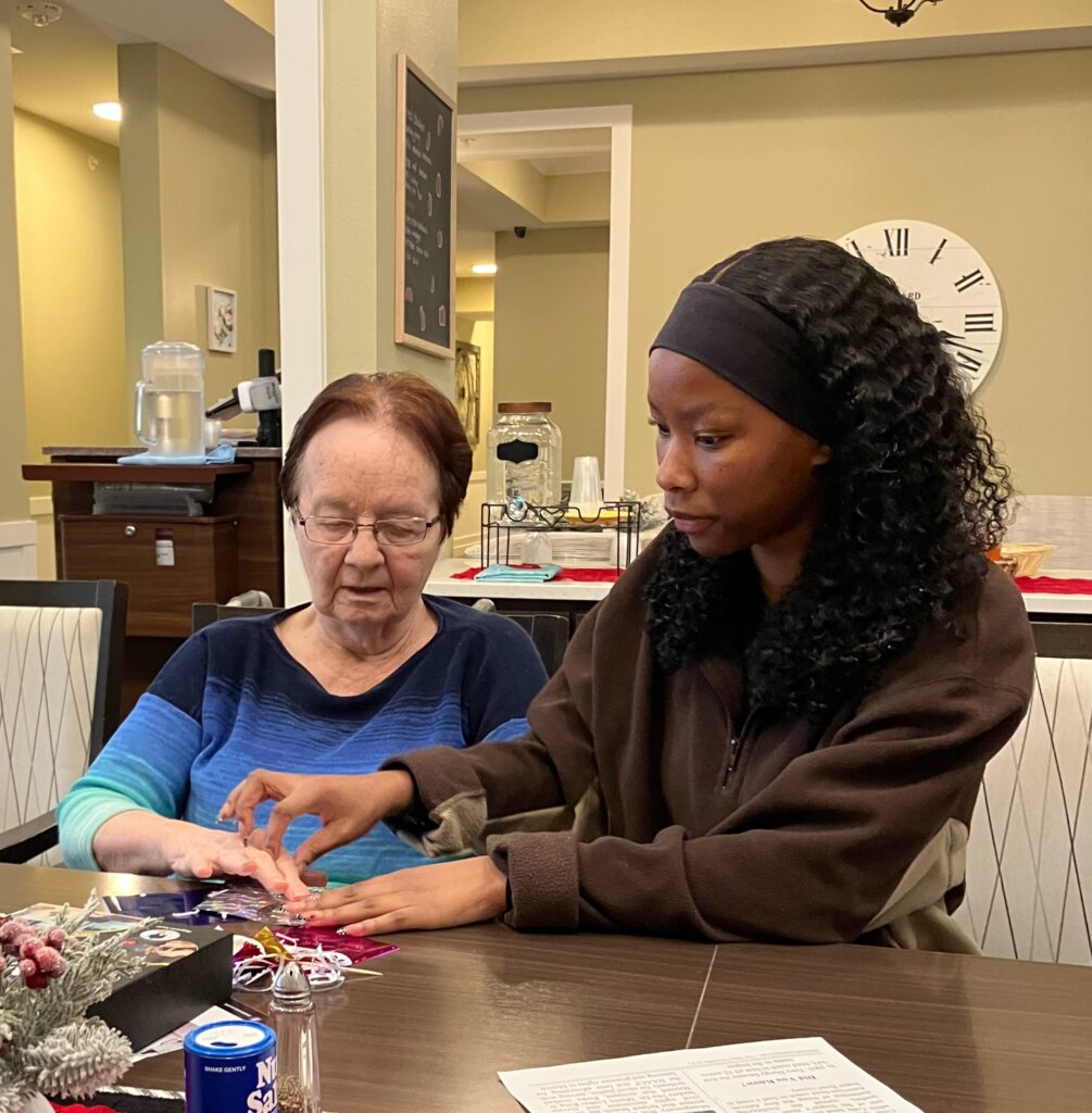 Resident and staff engaging in an activity at a table