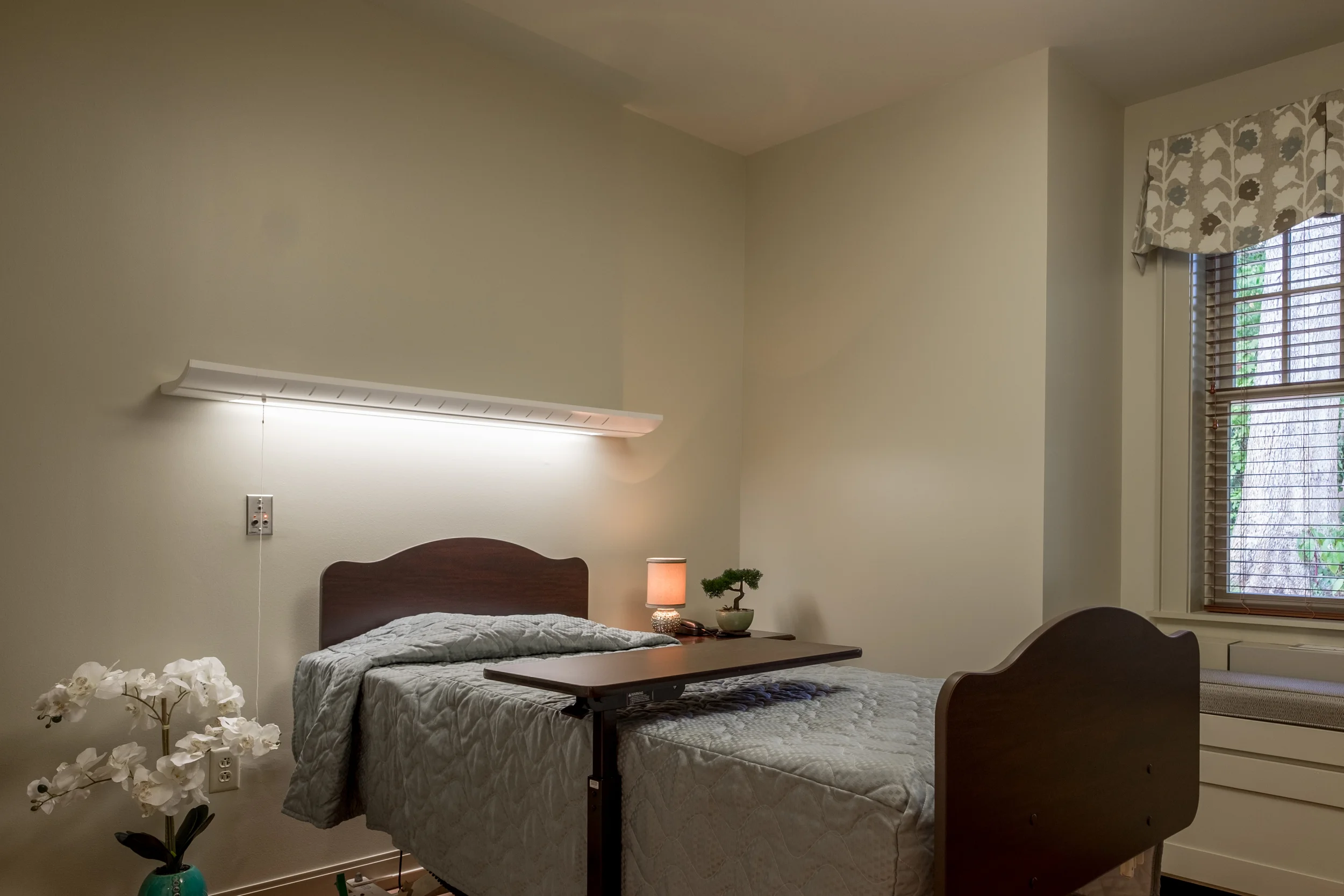 Interior view of a resident's room with a bed and lamp