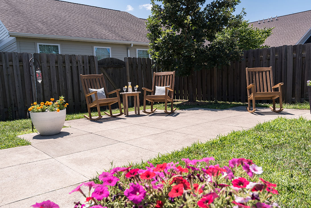 Outdoor patio area with rocking chairs and flowers