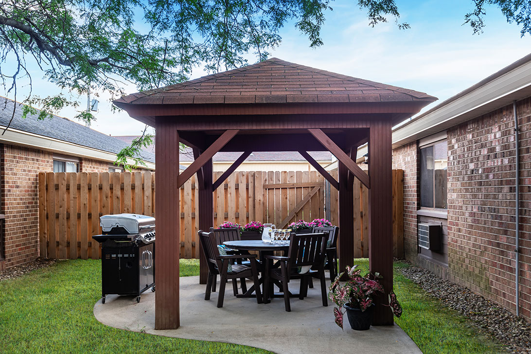 Outdoor gazebo with seating and grill in a courtyard