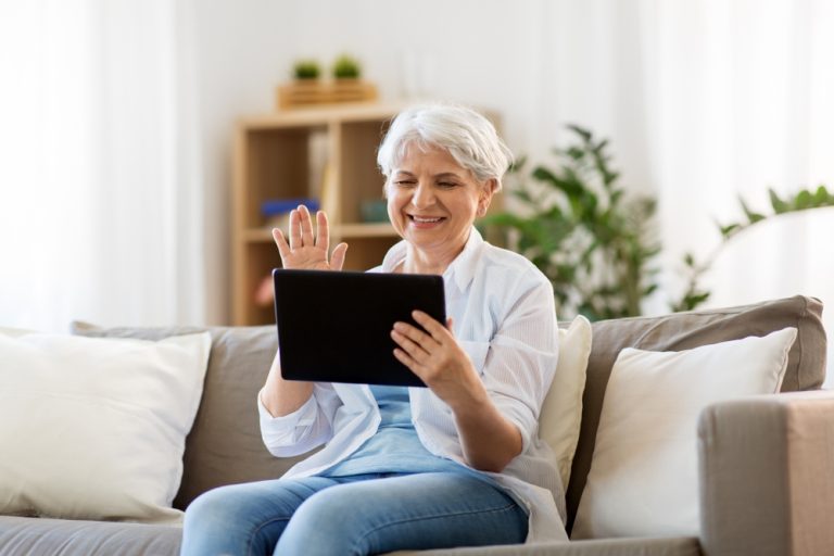 Senior woman video chatting on a tablet in a cozy living area