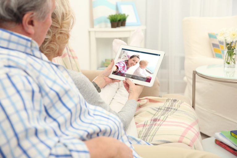 Elderly couple using a tablet to video chat with family