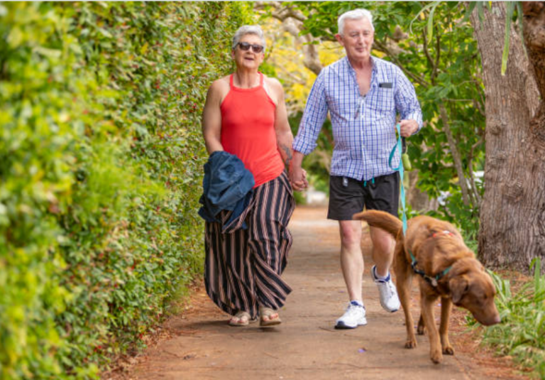 Couple walking a dog along a garden path