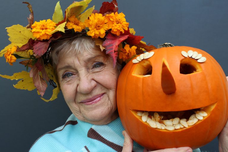 A resident holding a decorated pumpkin and smiling