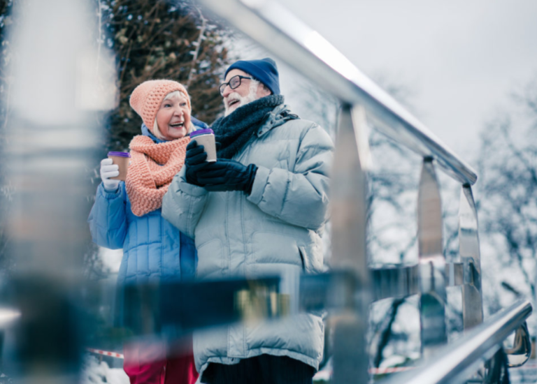 Elderly couple enjoying hot drinks outdoors in winter