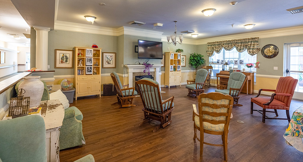 A common area with chairs and a television in a senior living facility