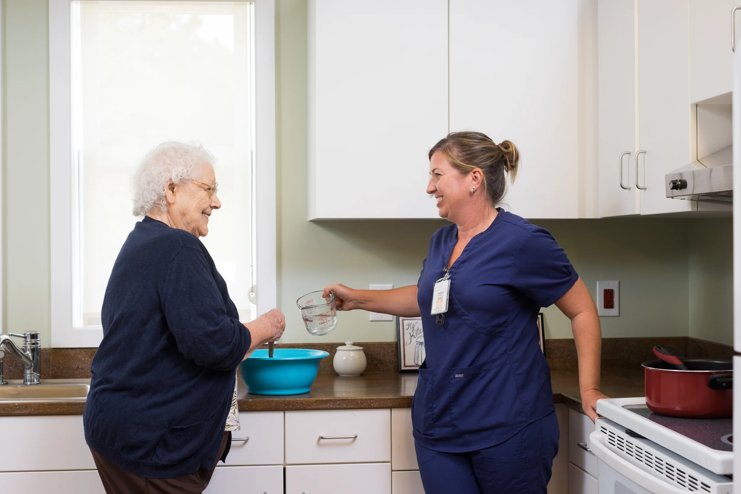 Caregiver assisting a resident in a light kitchen setting