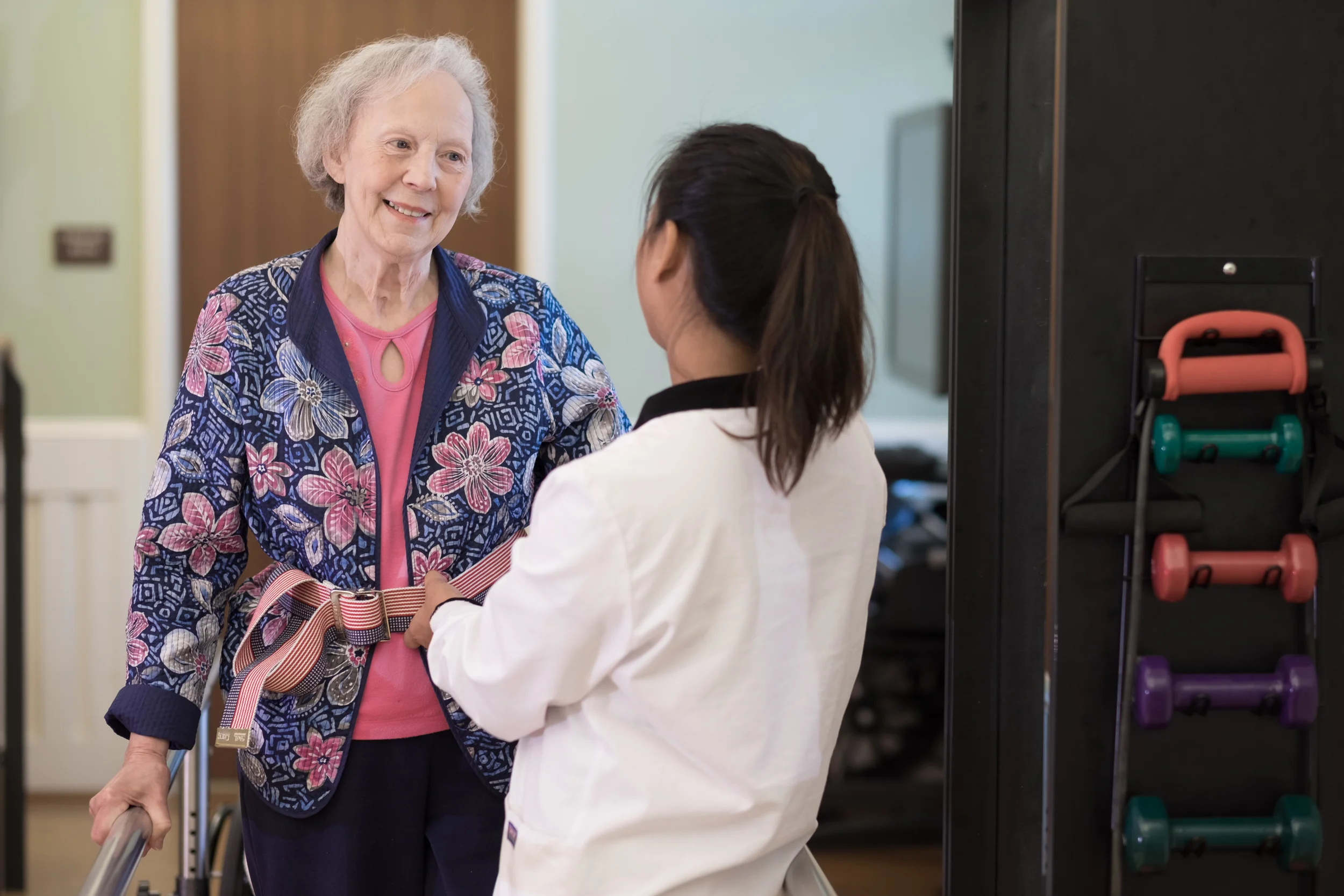 Staff assisting a smiling resident in a common area