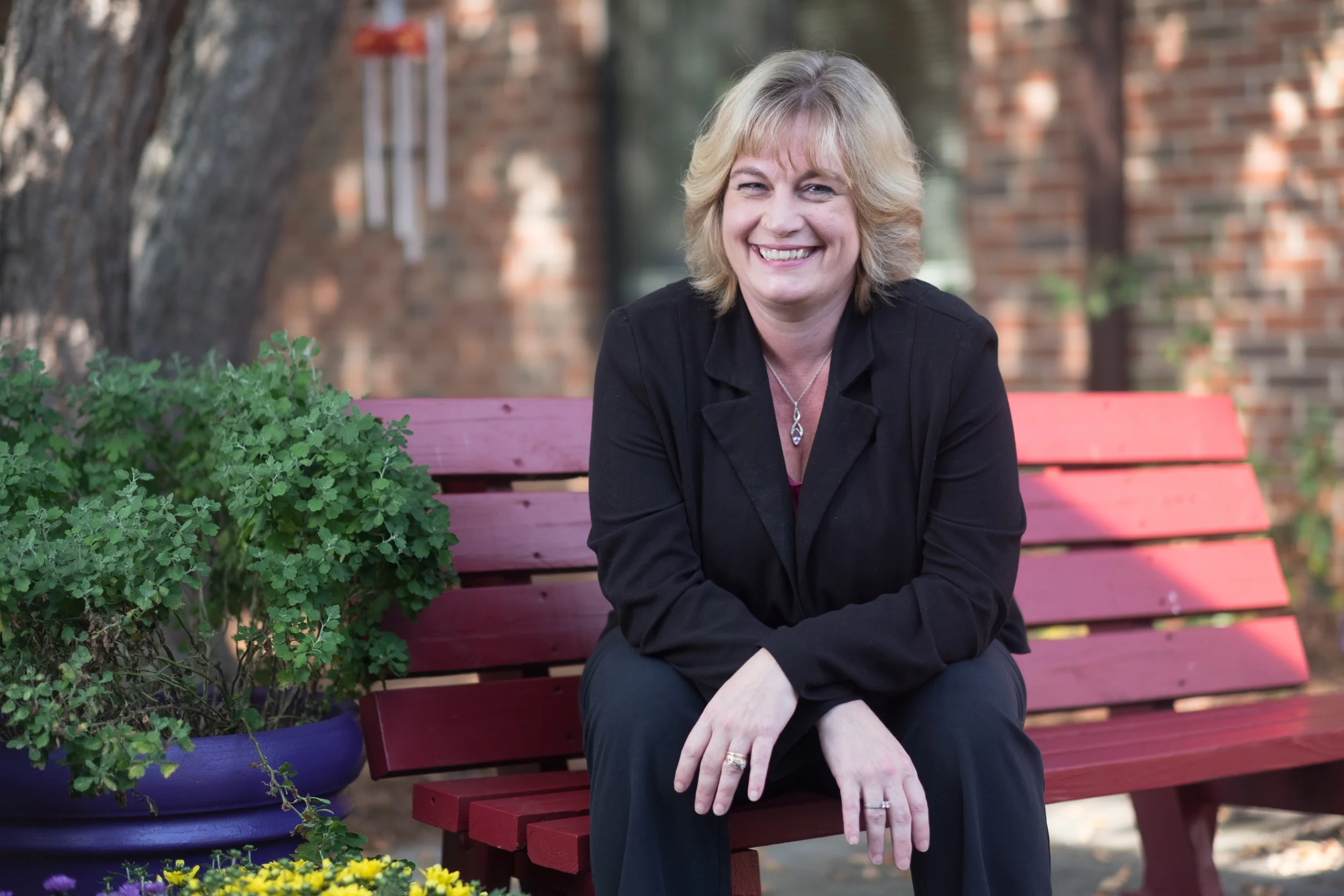 Smiling staff member sitting on a bench in the garden