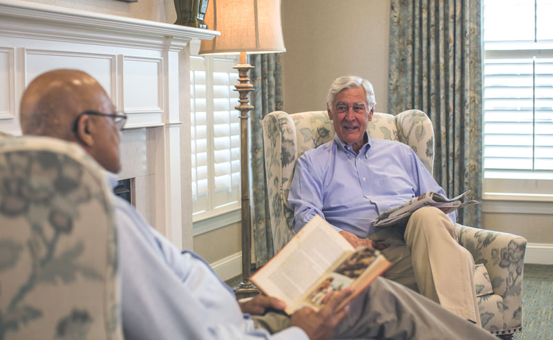 Two male residents reading indoors in a cozy setting