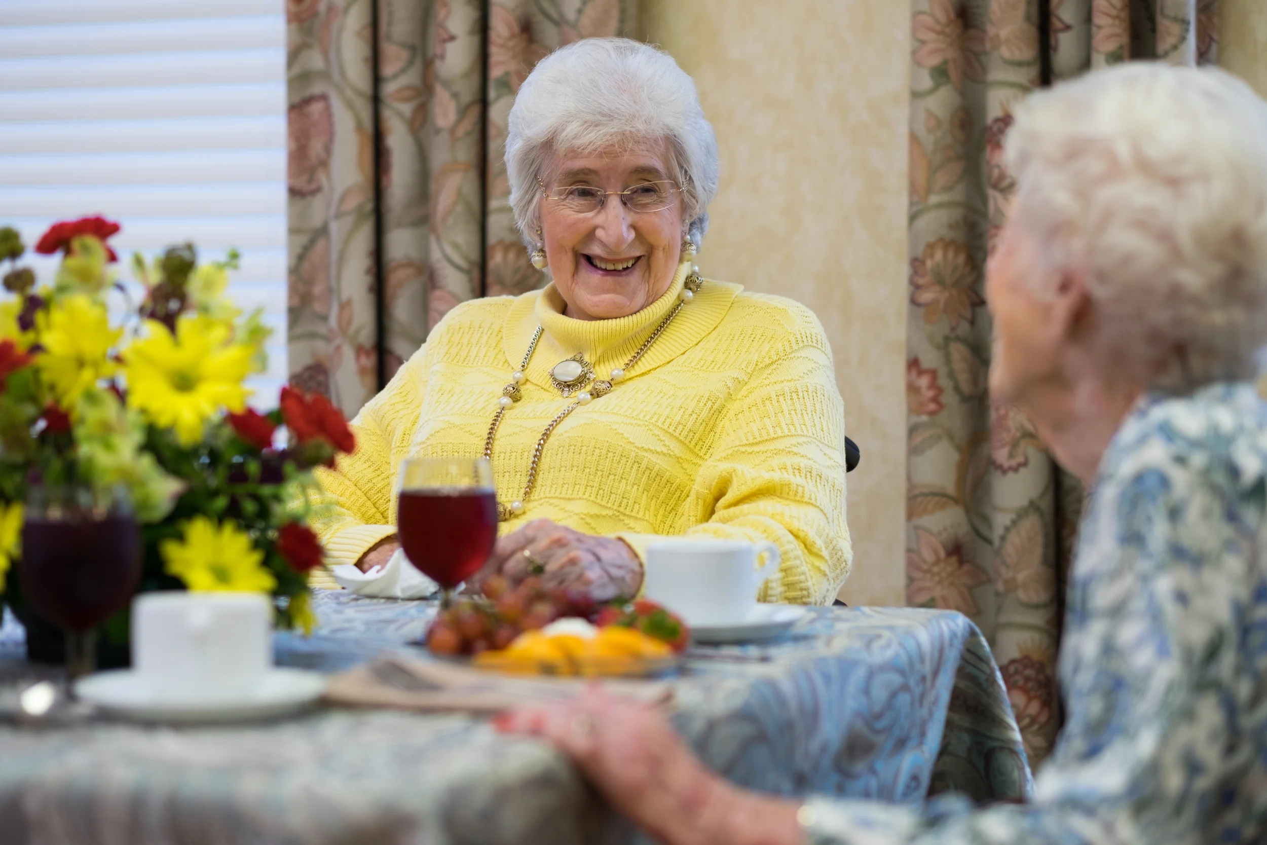 Two smiling elderly women enjoying a meal together